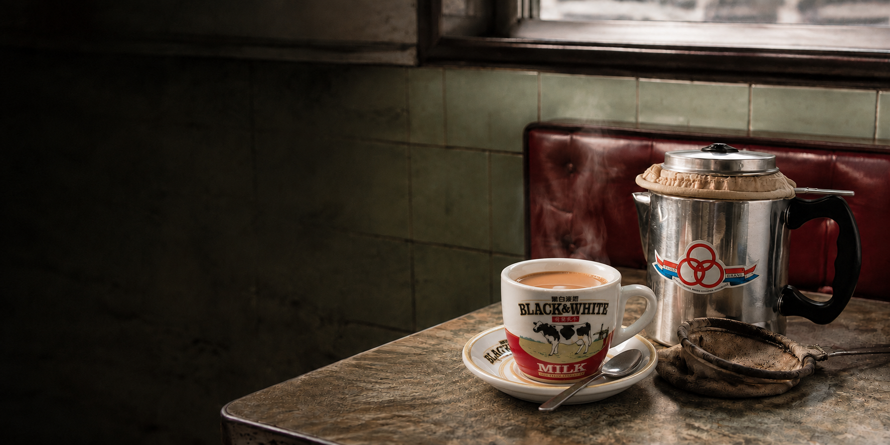 A classic ceramic cup of Hong Kong milk tea beside a Rings Brand tea pot and cloth filter in a cha chaan teng
